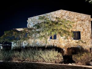 un edificio de piedra con un árbol delante de él en Olea bungalows, en Akrotiri