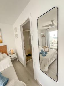 a mirror in a white room with a bed and a couch at Casa Burgao Studio with large seaview terrace in Punta de Mujeres