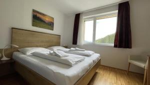 ein Schlafzimmer mit einem Bett mit weißen Laken und einem Fenster in der Unterkunft Apartmány ALPINE LIVING Haus - Schladming in Haus im Ennstal