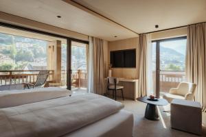 a hotel room with a bed and a balcony at Hotel COSMEA - Your Dolomites & Honeymoon experience in Ortisei