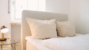a bed with white pillows and a table with a lamp at Apartment mit Balkon, Küche & Waschmaschine an der WHU in Vallendar
