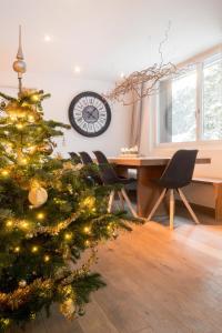 a christmas tree in a living room with a clock at Alpine Chic Apartment in Andermatt
