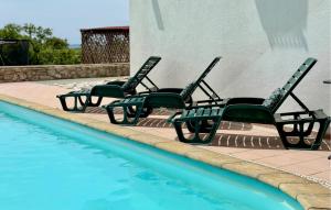 three green chairs sitting next to a swimming pool at 2 Bedroom Amazing Apartment In Labin in Diminići