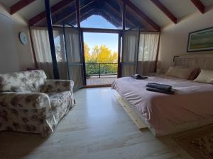 a bedroom with a bed and a chair and a window at Country Cottage Home in Chorazim