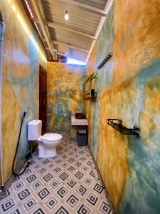 a bathroom with a toilet and a tiled floor at Alen's Stay&surf in Airsatang