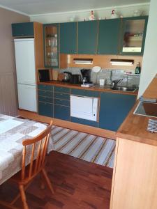 a kitchen with blue cabinets and a table with a chair at Feriehus med utsikt mot fjellet Hoven in Smedvik