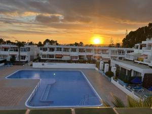 a pool on the roof of a building with a sunset at Estrella apartment in Costa Del Silencio