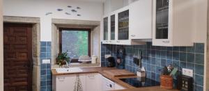 a kitchen with white cabinets and blue tiles on the wall at Casa Gallega Tradicional La Mar in A Guarda +33 photos