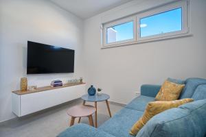 a living room with a blue couch and a tv at Mićos Beach Studio with Pool in Slatine