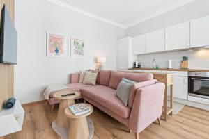 a living room with a pink couch and a kitchen at Mamalipa Apartments in Vienna