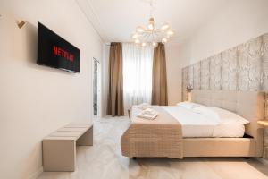 a white bedroom with a bed and a chandelier at Avenue Suites in Bologna