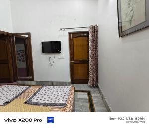 een kamer met 2 bedden en een deur met een televisie bij Vagary Indians Homestay in Dehradun