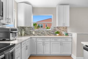 Una cocina con gabinetes blancos y una ventana. en Sea Gem Beach Slp 16 Amenities, en St. Augustine