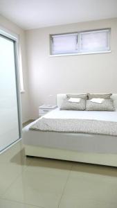 a white bedroom with a bed and a window at Lux trosoban in Sremska Mitrovica