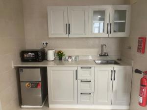 a kitchen with white cabinets and a sink and a refrigerator at AL Ghaith Hotel Apartment الغيث للأجنحة الفندقية in Salalah +40 photos