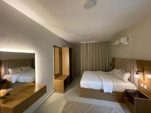 a hotel room with two beds and a desk at AL Ghaith Hotel Apartment الغيث للأجنحة الفندقية in Salalah