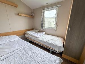 zwei Betten in einem kleinen Zimmer mit Fenster in der Unterkunft Lovely 6 Berth Caravan At St Osyth Beach Holiday Park In Essex Ref 28035Fi in Clacton-on-Sea