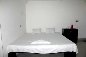 Collection O Bolpur Jambuni Bus Terminal في سانتينيكيتان: غرفة نوم مع سرير أبيض وخزانة سوداء