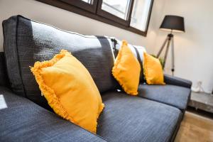 a blue couch with two yellow pillows on it at Résidence Le Jardin d'Eugénie in Sanary-sur-Mer
