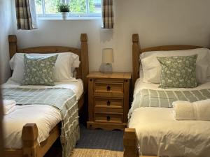 Un dormitorio con dos camas y una mesita de noche. en The Dairy Cotswolds Cottage Farm With Pool, en Lechlade