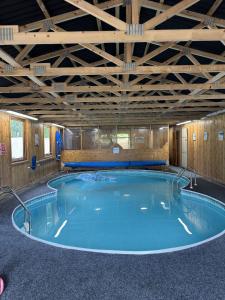 una gran piscina en un edificio con techo de madera en The Dairy Cotswolds Cottage Farm With Pool, en Lechlade
