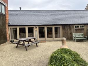 una mesa de picnic sentada frente a un edificio en The Dairy Cotswolds Cottage Farm With Pool, en Lechlade