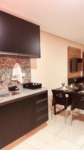 a kitchen with black cabinets and a dining table at Flat Residencial dos Anjos in Maceió +12 photos