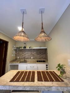 a kitchen with three lights hanging from the ceiling at Lofts Serena - No Centro de Itacaré, a passos da Pituba in Itacaré +17 photos