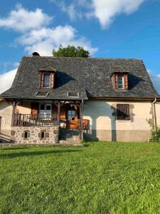 ein großes Haus mit grünem Rasen davor in der Unterkunft Gîte À La Ferme Au Puy Mary in Mandailles