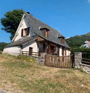 Ein altes Haus auf einem Hügel mit einem Zaun in der Unterkunft Gîte À La Ferme Au Puy Mary in Mandailles + 24 Fotos