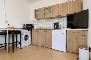 a kitchen with a washing machine and a tv at Sunflight Apt 01B One Bedroom Apt in Larnaca