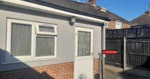 a white house with a white door and a gate at Parkside Studio in Luton