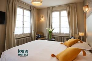 Un dormitorio con una gran cama blanca con almohadas amarillas. en Logis Hôtel Marguerite, en Orléans