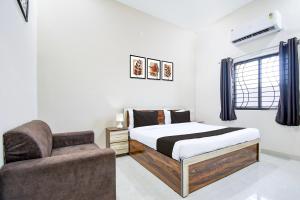 a bedroom with a bed and a chair at Hotel O KVR snuggle in Bilāspur