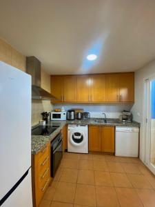 eine Küche mit Holzschränken und einem weißen Geschirrspüler in der Unterkunft Habitación en Bonalba con vistas al campo de golf in Mutxamel