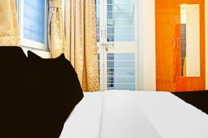 a white bed with black pillows in front of a window at Townhouse Surya Inn in Pune
