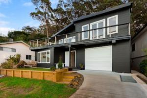 a black house with white doors and a driveway at Henderson House in Saratoga