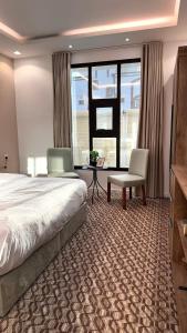 a hotel room with a bed and a desk and chairs at Roaa Al-Jamwaut in Al Madinah +9 photos