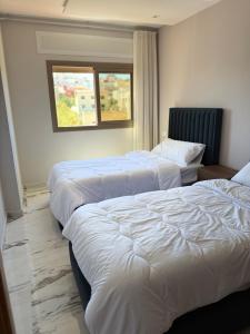 three beds in a hotel room with a window at Residence Plaza de Toros in Tangier