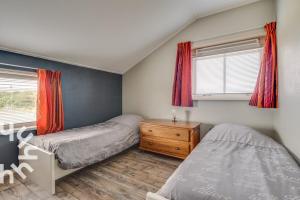 a bedroom with two beds and a dresser and windows at de Paardekracht in Serooskerke