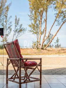 a rocking chair with a red pillow sitting on a sidewalk at Sea Beach - Loft em Frente ao Mar #1 in Sangão