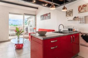 a red kitchen with a sink and a table at Appartement Honoré in Saint-François