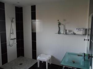 a bathroom with a sink and a shower and a stool at Gite bord de mer jacuzzi in Plougrescant +3 photos