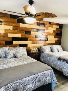 a bedroom with two beds and a wooden wall at Tropical Mountain Valley Casita in Mesa