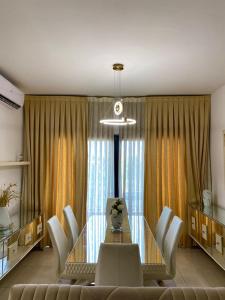a dining room with a glass table and white chairs at Appartement 211 in Dakar