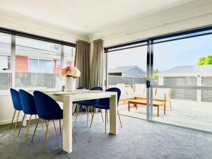 une salle à manger avec une table blanche et des chaises bleues dans l'établissement 6 Guests Family Home 7 Minutes to Airport, à Christchurch