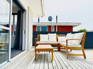 un patio avec un banc et une table sur une terrasse dans l'établissement 6 Guests Family Home 7 Minutes to Airport, à Christchurch