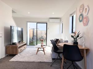 a living room with a television and a table and chairs at New Luxury town house on Salisbury with 65 TV in Christchurch