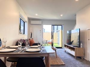a dining room with a table and a tv at New 3 Storey luxe townhouse on quiet street in Christchurch