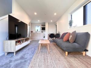 a living room with a couch and a flat screen tv at New 3 Storey luxe townhouse on quiet street in Christchurch